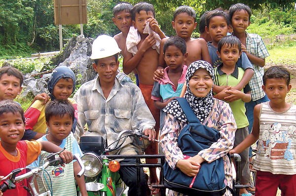 Tri Mumpuni Iskandar (front row, second from r., with villagers in Aceh, Indonesia) developed microh