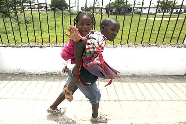 A boy carries his sister along a street after classes in Bata, Equatorial Guinea, in west central Af