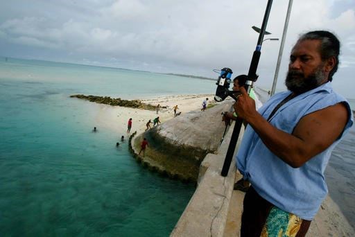 In this March 30, 2004, file photo, a man fishes on a bridge on Tarawa atoll, Kiribati. The island nation of Kiribati established a large shark sanctuary that will help ensure the creatures are protected across much of the central Pacific. Vice President Kourabi Nenem said at the sanctuary’s launch on Friday, Nov. 18, 2016, that the nation was committed to protecting sharks from exploitation and overfishing. (AP Photo/Richard Voge, File)
