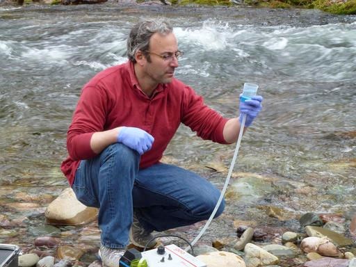 This April 17, 2014 photo provided by the U.S. Forest Service shows Michael K. Schwartz in the process of filtering 5 liters of water to concentrate DNA on a filter to be analyzed at the National Genomics Center for Wildlife and Fish Conservation, on Rattlesnake Creek near Missoula, Mont. Scientists are aiming to create a biodiversity map that identifies thousands of aquatic species in every river and stream in the western United States. They say that by next summer, the first Aquatic Environmental DNA Atlas will be available to the public. (Kellie Carim/U.S. Forest Service via AP)