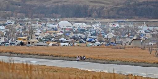 In this Nov. 24, 2016 photo, people stand on the edge of Cantapeta Creek near the growing Sacred Stones Overflow Protest Camp in Morton County, N.D. The leader of the Cheyenne River Sioux in South Dakota is calling for all opponents of the Dakota Access oil pipeline to boycott businesses in North Dakota's capital city. (Tom Stromme/Bismarck Tribune via AP)