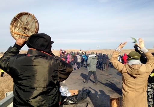 Protesters against the Dakota Access oil pipeline congregate Monday, Nov. 21, 2016, near Cannon Ball, N.D., on a long-closed bridge on a state highway near their camp in southern North Dakota. The bridge was the site of the latest skirmish between protesters and law officers, in which officers used tear gas, rubber bullets and pepper spray, and authorities say protesters assaulted officers with rocks and burning logs. (AP Photo/James MacPherson)