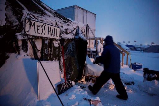 Ray Franks, of New York, carries a case of water into a mess hall at the Oceti Sakowin camp where people have gathered to protest the Dakota Access oil pipeline in Cannon Ball, N.D., Tuesday, Dec. 6, 2016. An overnight storm brought several inches of snow, winds gusting to 50 mph and temperatures that felt as cold as 10 degrees below zero. (AP Photo/David Goldman)
