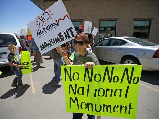 This July 14, 2016, file photo, a protester holds her signs after U.S. Interior Secretary Sally Jewell arrived for a meeting with San Juan County Commissioners in Monticello, Utah. President Barack Obama designated two national monuments Wednesday, Dec. 28, at sites in Utah and Nevada that have become key flashpoints over use of public land in the U.S. West. The White House says Bears Ears National Monument in Utah will cover 1.35 million acres of tribal land in the Four Corners region. (AP Photo/Rick Bowmer, File)