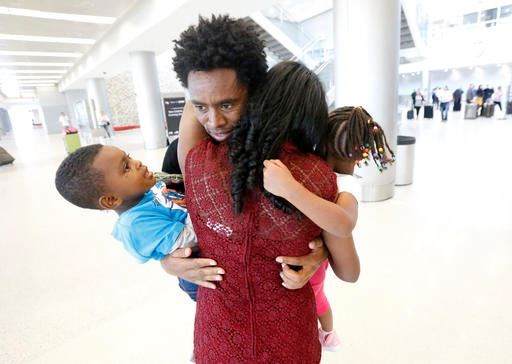 Olympic silver medalist Feyisa Lilesa, rear, of Ethiopia, hugs his wife Iftu Mulia, his daughter Soko, right, 5, and son Sora, left, 3, while picking up his family at Miami International Airport, Tuesday, Feb. 14, 2017, in Miami. Lilesa arrived in the U.S. on a special skills visa, which allows him to train and compete until January. His wife, son, daughter and brother joined him in Miami Tuesday. (AP Photo/Wilfredo Lee)