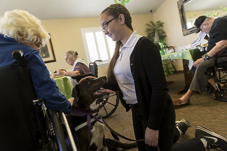 Resident Irma Porter pets Lucy as she and her owner Alexandra Burnham visit residents at the Beehive Homes in Farmington, N.M. (Jon Austria/The Daily Times/AP)