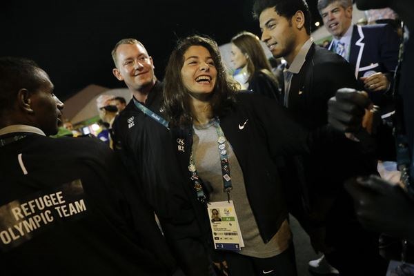 Refugee Olympic Team's Yusra Mardini, center, smiles during a welcome ceremony at the Olympic Village on Aug. 3, ahead of the Olympics in Rio de Janeiro. Ms. Mardini, who fled Syria's civil war, is one of 10 athletes competing this year in an all-refugee team under the Olympic flag. Photo: Jae C. Hong/AP