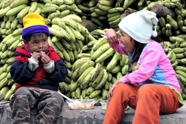 Children eat in front of a huge pile of bananas in La Paz, Bolivia. A school-feeding program run by Samaritan's Purse delivers food to 72 rural schools with 28,000 children while helping Bolivian farmers grow crops. <P>Gaston Brito/Reuters/File