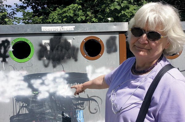 Irmela Mensah-Schramm points to a garbage bin that had been decorated with Nazi symbols before she painted over them in Zossen, Germany. <P> Isabelle de Pommereau