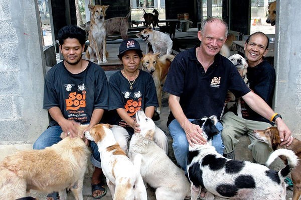 John Dalley (second from r.) relaxes with Soi Dog Foundation staffers and dogs rescued from Thailand's illegal dog meat trade. <P>Courtesy of John Dalley