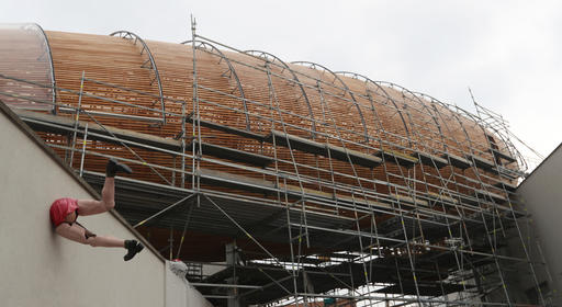 In this Monday, Sept. 19, 2016 photo a giant object resembling a zeppelin airship is being installed on the rooftop of an arts center in Prague, Czech Republic. The 42-meter long and 10-meter wide ship is planned to seat some 120 people on its cascade steps. It will be used for authors' reading and debates about literature to complement exhibitions at the DOX Centre for Contemporary Art, one of the most innovative and challenging galleries in the Czech capital. (AP Photo/Petr David Josek)