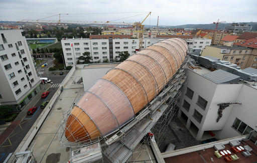 A giant object resembling a zeppelin airship is being installed on the rooftop of an arts center in Prague, Czech Republic, Monday, Sept. 19, 2016. The 42-meter long and 10-meter wide ship is planned to seat some 120 people on its cascade steps. It will be used for authors' reading and debates about literature to complement exhibitions at the DOX Centre for Contemporary Art, one of the most innovative and challenging galleries in the Czech capital. (AP Photo/Petr David Josek)