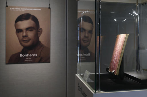 In this Thursday, March 19, 2015 file photo, a notebook of British mathematician and pioneer in computer science Alan Turing, the World War II code-breaking genius, is displayed in front of his portrait during an auction preview in Hong Kong. Britain's government will posthumously pardon thousands of gay and bisexual men convicted under long-repealed anti-gay laws. The calls for a more sweeping action came after World War II codebreaker Alan Turing was awarded a posthumous royal pardon in 2013 after a conviction of indecency in 1952. The gay computer science pioneer was stripped of his security clearance and later committed suicide. (AP Photo/Kin Cheung, File)