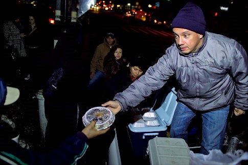 Jorge giving food to hungry people<br>(http://assets.nydailynews.com)