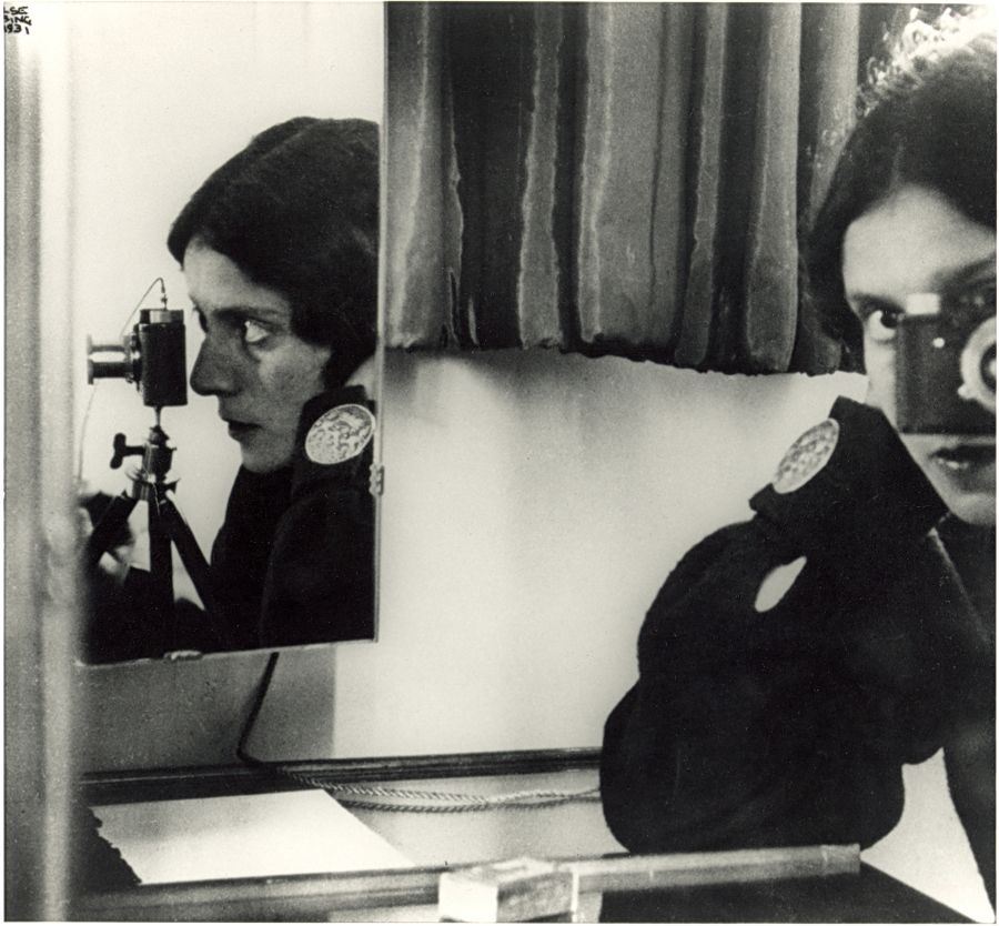Self-portrait of Ilse Bing with camera, in front of a mirror reflection of herself.
