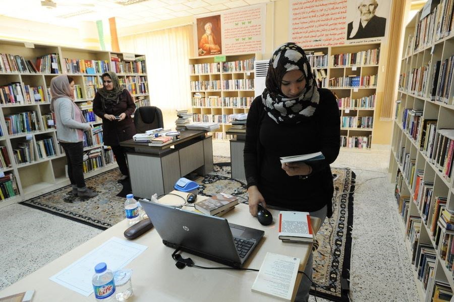 Iraqi student Amal Hussein works as a library assistant scanning books in a local public library during her fourth year on scholarship at the American University of Iraq in the Kurdish northern city of Sulaimaniyeh, Iraq, on March 6, 2014. Ms. Hussein is the daughter of the widowed Baghdad matriarch Karima Selman Methboub, whose impoverished family of nine The Christian Science Monitor has reported upon extensively throughout the Iraq war and since late 2002, when Saddam Hussein was still in power. Photo: Scott Peterson, Getty Images