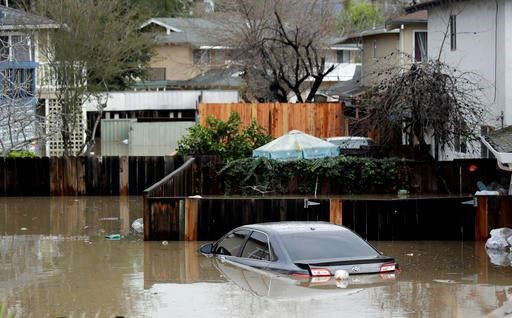 Cars and backyards are flooded in a neighborhood Tuesday, Feb. 21, 2017, in San Jose, Calif. Rescuers chest-deep in water steered boats carrying dozens of people, some with babies and pets, from a San Jose neighborhood inundated by water from an overflowing creek Tuesday. (AP Photo/Marcio Jose Sanchez)