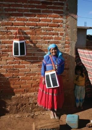 Estella Hernandez wears her Portable Light Unit integrated into a traditional Huichol carry bag while another charges on the wall. Photo credit: Kennedy & Violich Architecture, LTD.