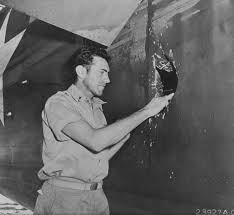 Zamperini looking at a bullet hole in his plane. (en.wikapedia.org ())