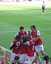 Fabregas is celebrating a goal with his team-mates (wkipedia ())