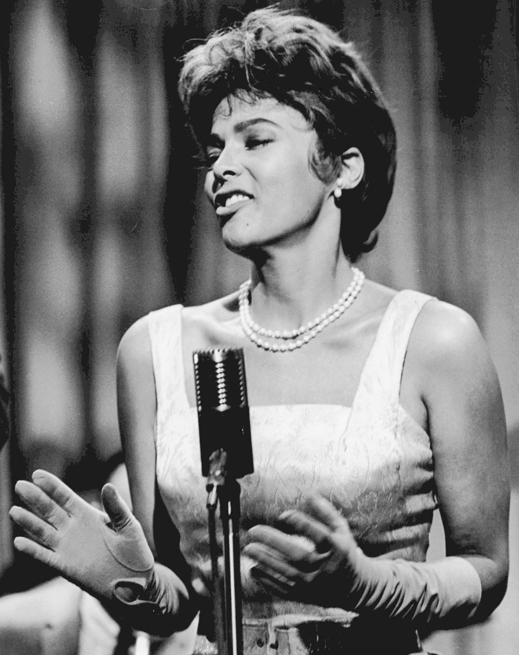 Photo of actress Dorothy Dandridge singing in evening dress in front of a mic