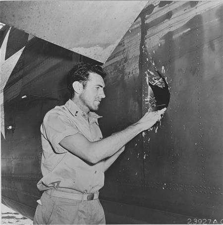 Louis Zamperini looking at a hole in his B-24 (theunwrittenrecord.files.wordpress.com ())