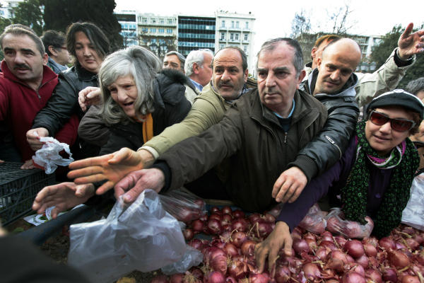 Greeks wait to receive free onions and other vegetables offered by farmers in Syntagma Square in Athens last January. In the US, many organizations work to share leftover fruits and vegetables with those in need, based on the ancient idea known as gleaning. <P>Yannis Behrakis/Reuters/File