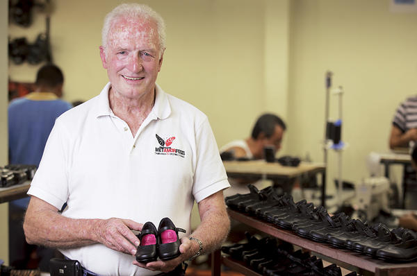 Sam Hawkins, cofounder of Love Link and the Metamorfosis project in El Salvador, holds a pair of high-quality shoes made by ex-convicts.