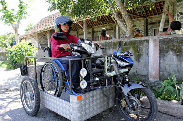 Sri Lestari of Central Java, Indonesia, demonstrates how she rides a modified motorcycle that can be operated from a wheelchair.  <P>Joni Sweet