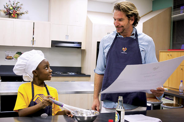 Charlie Weingarten reads the Common Threads creed as Kemai Richardson finishes stirring some dipping sauce during a Common Threads cooking class in Los Angeles. The program, one of many projects started by Mr. Weingarten, aims to teach children to love healthy cooking and eating.  <P>David Ahntholz