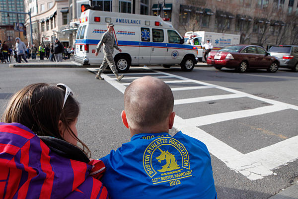 A couple sits on the sidewalk at an intersection where police have closed the road because of another bomb scare at a nearby hotel, on Monday in Boston, Massachusetts. All along the marathon route spectators came to the aid of runners offering drinks, blankets, cell phone calls, and even taking runners into their homes.  <P>Melanie Stetson Freeman/TCSM
