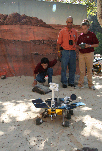 <h6>JASON Student Argonaut Janelle Wilson drives a Mars rover prototype at NASA Jet Propulsion Laboratory as Student Argonaut Antonio Campos and NASA Senior Mechanical Engineer, Kobie Boykins, look on.  <p></h6>