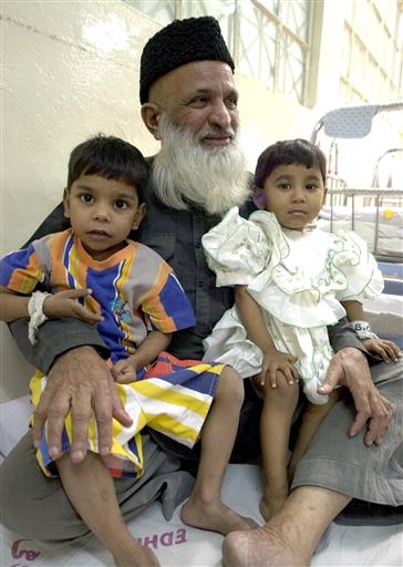In this March 16, 2002 file photo, Pakistan's renowned social worker Abdul Sattar Edhi holds infants at Edhi Childcare Center in Karachi, Pakistan. The family of Pakistan's legendary philanthropist Abdul Sattar Edhi say he has died at a hospital in Karachi. (AP Photo)
