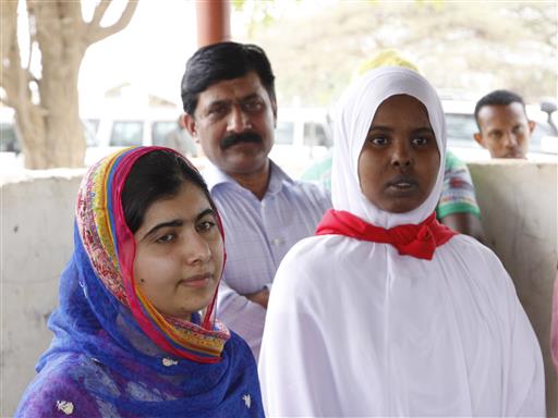 Malala Yousafza, left, with an escort, visits the Dadaab camp, in Kenya, Tuesday, July 12, 2016. Nobel laureate Malala Yousafzai is spending her 19th birthday in Kenya Tuesday visiting the world's largest refugee camp to draw attention to the global refugee crisis, especially as Dadaab camp faces pressure to close after a quarter-century. (AP Photo/Khalil Senosi)