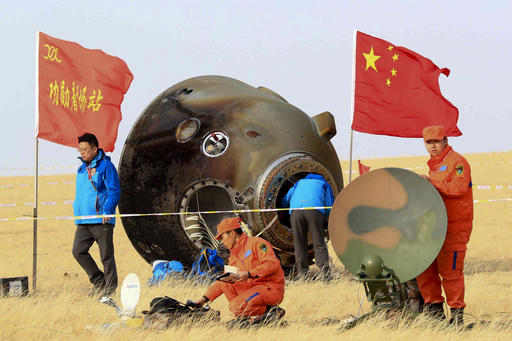 In this photo released by Xinhua News Agency, ground crew check on the re-entry capsule of Shenzhou 11 spacecraft after it landed in north China's Inner Mongolia Autonomous Region, Friday, Nov. 18, 2016. A pair of Chinese astronauts returned Friday from a monthlong stay aboard the country's space station, China's sixth and longest crewed mission and a sign of the growing ambitions of its rapidly advancing space program. (Li Gang/Xinhua via AP)