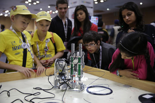 In this Sunday, Nov. 27, 2016 photo, participants and spectators look at a 3D printer made of LEGO parts during the World Robot Olympiad in New Delhi, India. The weekend games brought more than 450 teams of students from 50 countries to the Indian capital. (AP Photo/Tsering Topgyal)