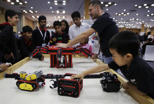 In this Sunday, Nov. 27, 2016, photo, a boy plays with a robot during the World Robot Olympiad in New Delhi, India. The weekend games brought more than 450 teams of students from 50 countries to the Indian capital. (AP Photo/Tsering Topgyal)