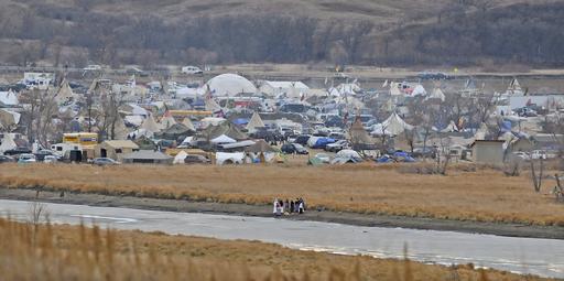 In this Nov. 24, 2016 photo, people stand on the edge of Cantapeta Creek near the growing Sacred Stones Overflow Protest Camp in Morton County, N.D. The leader of the Cheyenne River Sioux in South Dakota is calling for all opponents of the Dakota Access oil pipeline to boycott businesses in North Dakota's capital city. (Tom Stromme/Bismarck Tribune via AP)