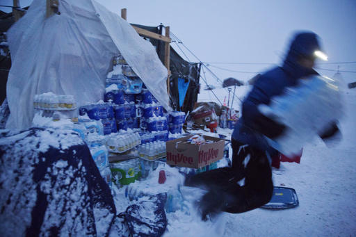 Ray Franks, of New York, trips while carrying a case of water from a storage supply at the Oceti Sakowin camp where people have gathered to protest the Dakota Access oil pipeline in Cannon Ball, N.D., Tuesday, Dec. 6, 2016. Many Dakota Access oil pipeline opponents who've gathered for months in the camp are committed to staying despite wintry weather and demands that they leave. An overnight storm brought several inches of snow, winds gusting to 50 mph and temperatures that felt as cold as 10 degrees below zero. (AP Photo/David Goldman)