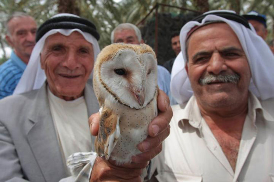 Palestinian and Israeli Arab farmers smile while holding a barn owl at a joint seminar in Israel. (Courtesy of Hagai Aharon)