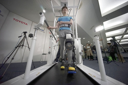 A model demonstrates the Welwalk WW-1000, a wearable robotic leg brace designed to help partially paralyzed people walk at the main system with treadmill and monitor, at Toyota Motor Corp.'s head office in Tokyo, Wednesday, April 12, 2017. Toyota Motor Corp.'s Welwalk WW-1000 system is made up of a motorized mechanical frame that fits on a person’s leg from the knee down. (AP Photo/Eugene Hoshiko)