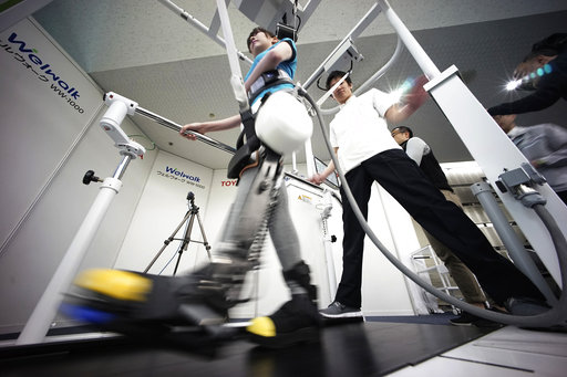 A model demonstrates the Welwalk WW-1000, a wearable robotic leg brace designed to help partially paralyzed people walk at the main system with treadmill and monitor, at Toyota Motor Corp.'s head office in Tokyo, Wednesday, April 12, 2017. Toyota Motor Corp.'s Welwalk WW-1000 system is made up of a motorized mechanical frame that fits on a person’s leg from the knee down. (AP Photo/Eugene Hoshiko)