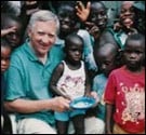 Richard sitting next to kids in Honduras. (http://www.kidsagainsthunger.org/<br>images/ourfounder)